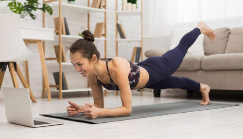 woman doing pilates in her living room from a computer screen