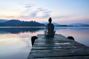 Woman sitting on a dock at sunset, calm, anxiety free