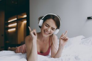 woman in bed, listening to music, dancing with fingers