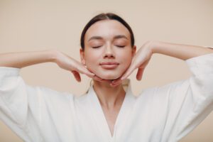 woman doing face yoga, in a robe